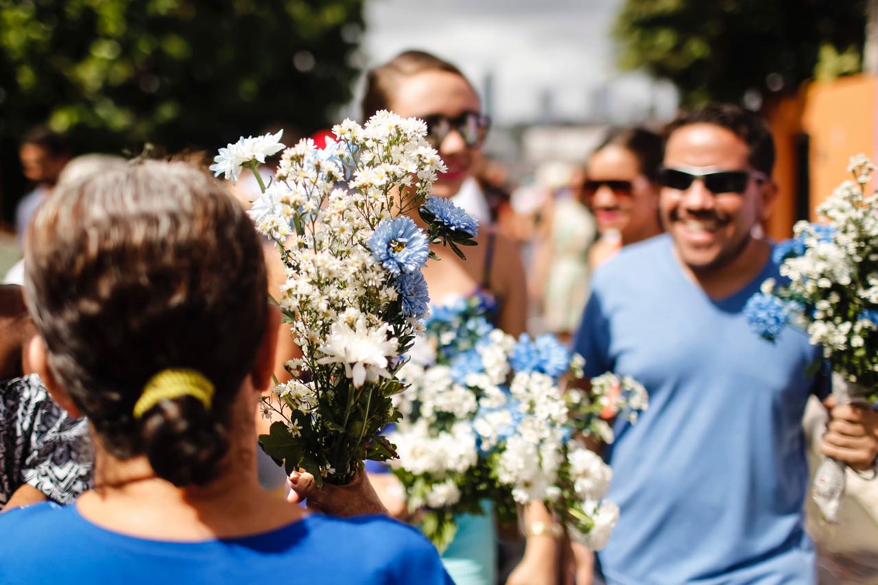 A foto mostra pessoas vestidas de azul, carregando flores brancas, em homenagem a Nossa Senhora da Conceição. Crédito: Andréa Rêgo Barros.